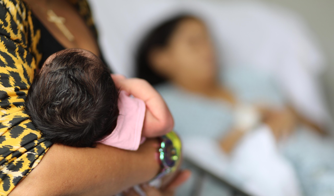 a foto mostra uma pessoa segurando um bebê no colo